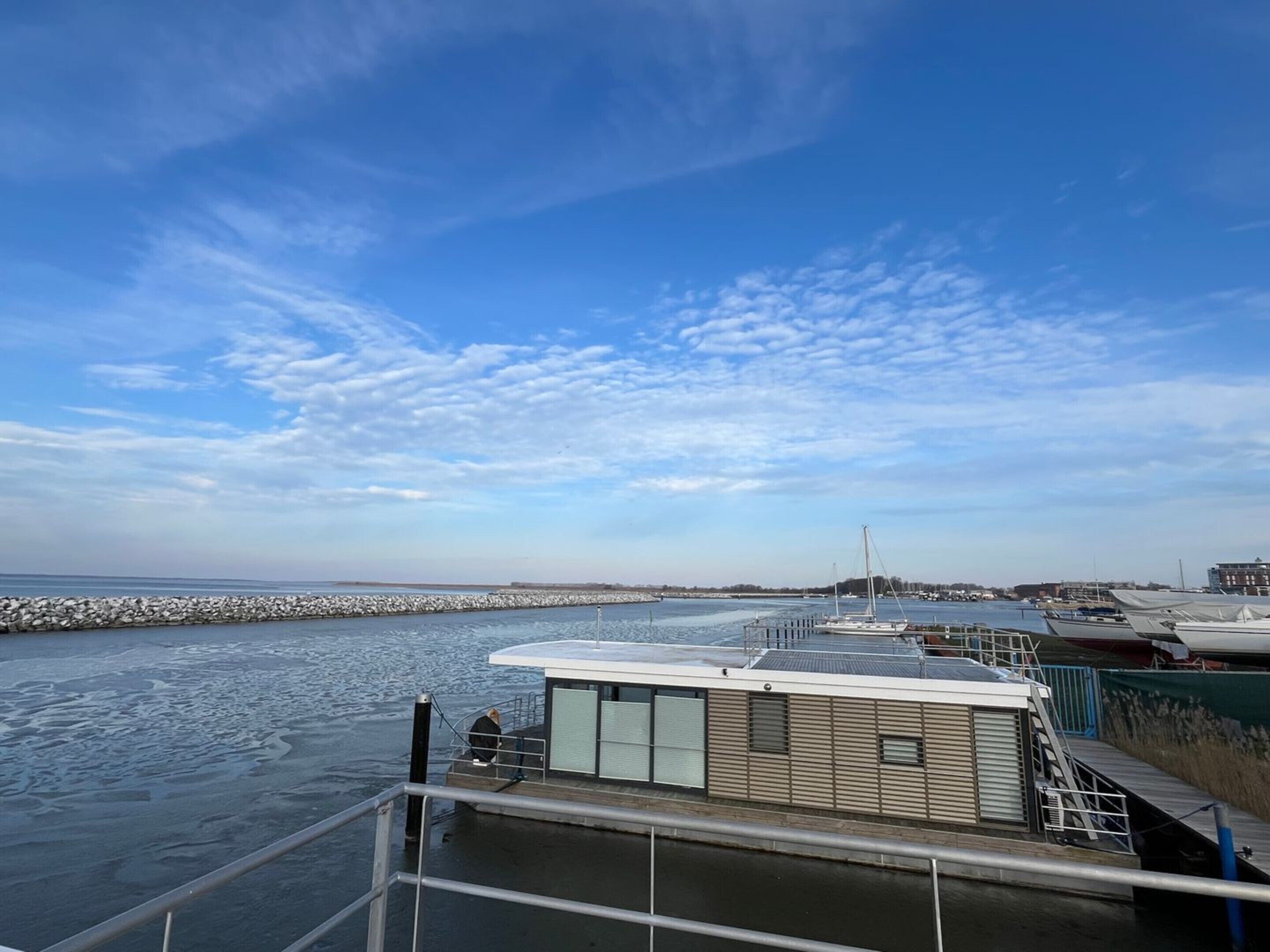 Vista al agua con muelle, un pequeño edificio con techo y cielo despejado.