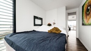 A bedroom with a large bed, a window with blinds, a wall-mounted light, and a view of the outdoors. - Hausboot in Barth am Barther Bodden (Barth)