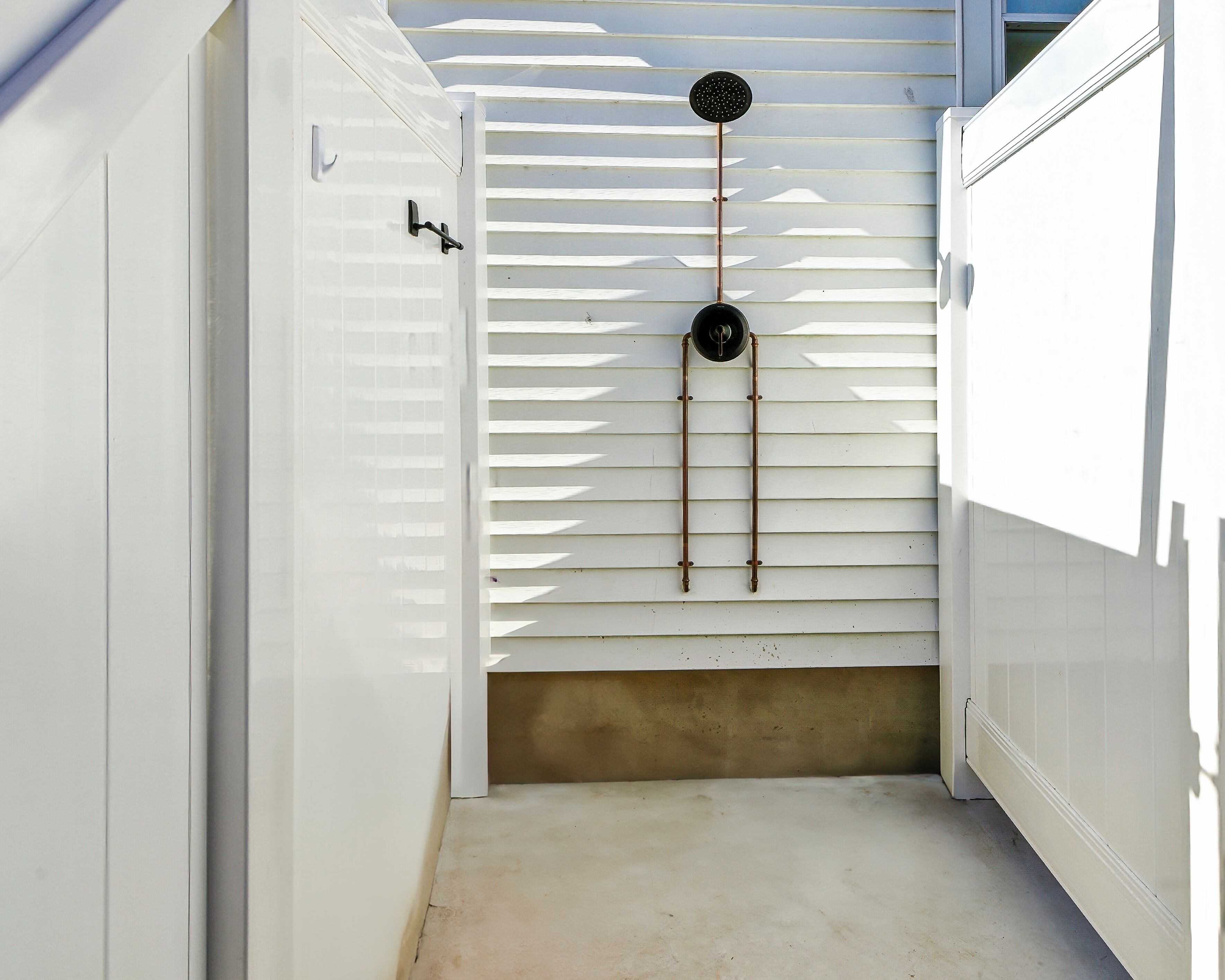 A narrow hallway with white walls and a concrete floor.