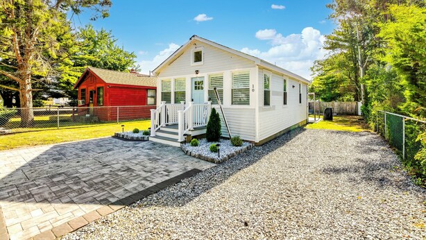 A single-story house with a front porch, a small deck, and a gravel driveway. - Bayside Bliss (Lower Township)