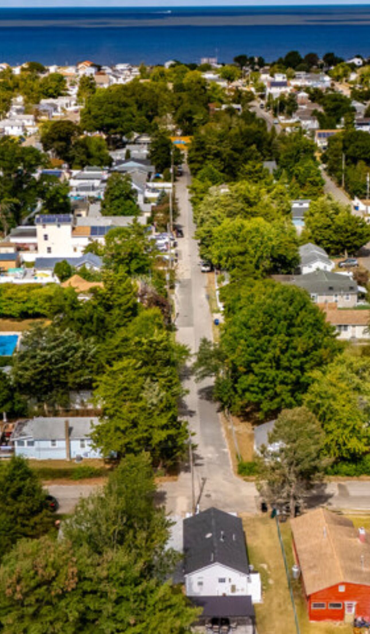 An aerial view of a residential area with houses, trees, and a road.