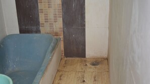 A small bathroom with a bathtub, a wooden floor, and tiled walls. - Charming 3-bedroom bungalow with AC, fitness room in wonderful Gwalior (GWALIOR)