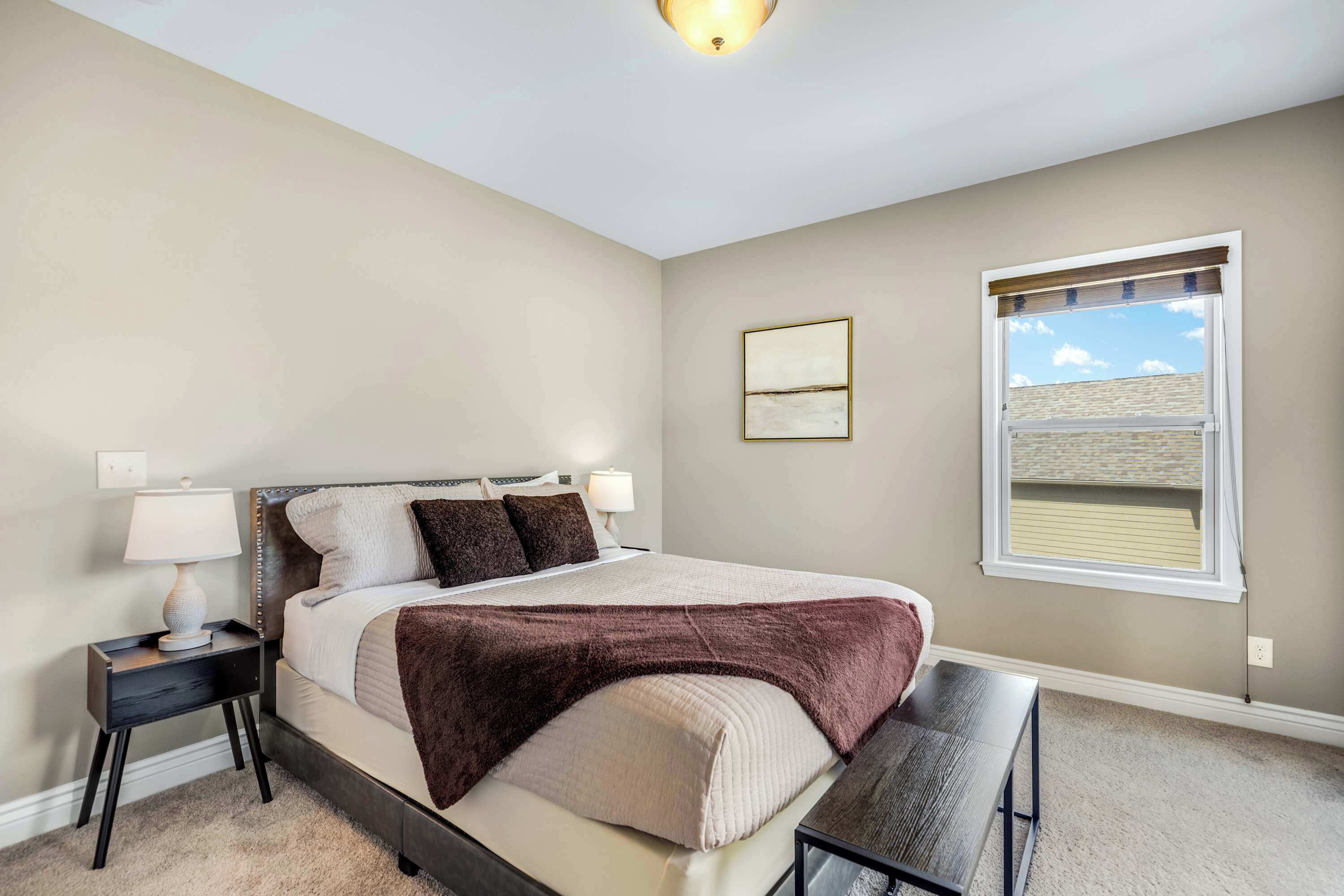 A bedroom with a bed, bedside tables, a window, and a ceiling light.