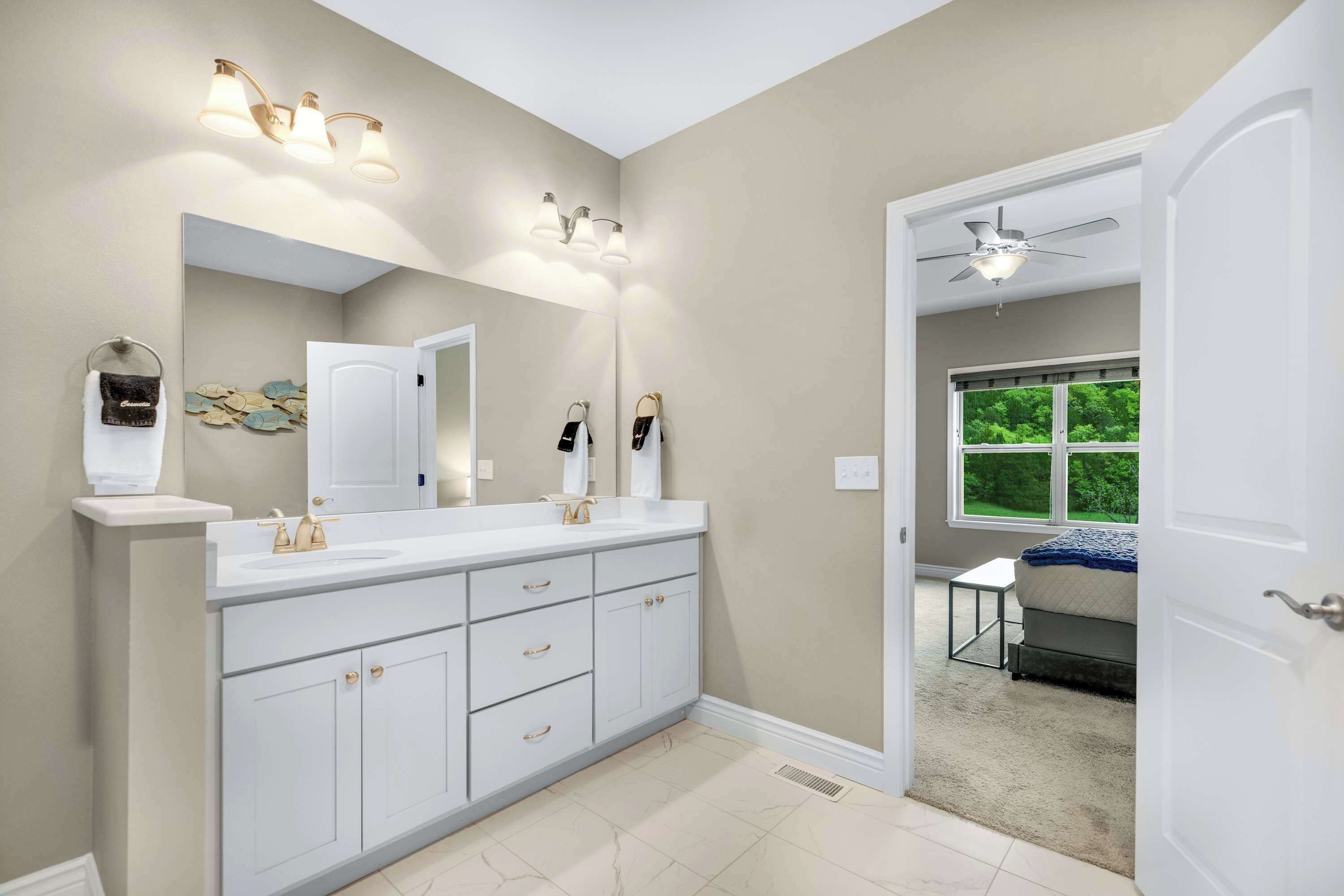 Un baño moderno con un mueble de tocador espacioso, lavamanos dobles y un ventilador de techo.