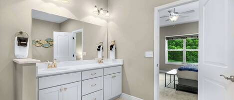 Un baño moderno con un mueble de tocador espacioso, lavamanos dobles y un ventilador de techo.