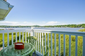 A balcony with a view of a river, green chairs, and a red pot on a table. - Swing Bridge #40 (Douglas)
