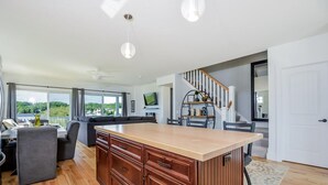 Una cocina moderna con una isla central, armarios de madera y una zona de comedor con mesa y sillas.
