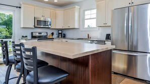 Una cocina moderna con una isla grande, electrodomésticos de acero inoxidable y vistas al exterior.