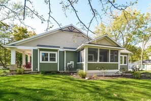 A two-story house with a covered porch and a screened porch.