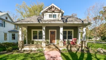 A two-story house with a front porch, a stone foundation, and a number 444 on the door.