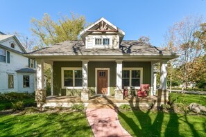 A two-story house with a front porch, a stone foundation, and a number 444 on the door. - Four Generations (Saugatuck)