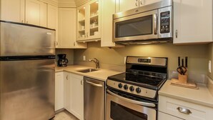 Una cocina moderna con electrodomésticos de acero inoxidable, incluyendo un refrigerador, microondas, estufa y horno.
