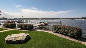 A lakeside dock with a flag, a red vehicle, and boats in the background. - Lay By The Bay (Saugatuck)
