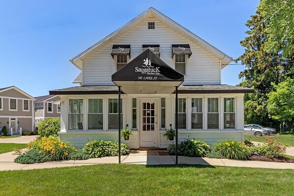 A two-story building with a white facade, large windows, and a black awning with the name "Saugatuck Harbor Inn" and address "787 Lake St." - Saugatuck Harbor House (Saugatuck)