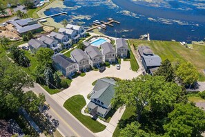 Ovenudblik over et boligområde med huse, en swimmingpool og en anløbsbro ud til en sø.