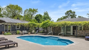 A backyard with a swimming pool, lounge chairs, and a pergola with climbing plants. - Captains Cove and Crew Quarters (Douglas)