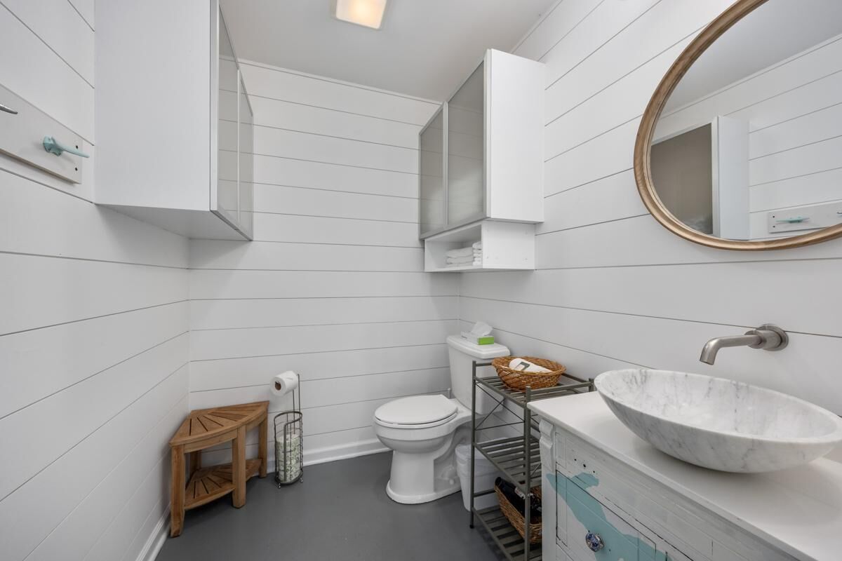 A bathroom with a white sink, toilet, and vanity.