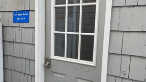 A gray door with a white window and a blue sign above it. - Downtown View (Saugatuck)