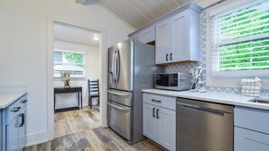 Una cocina moderna con electrodomésticos de acero inoxidable, suelo de madera y vistas al exterior.