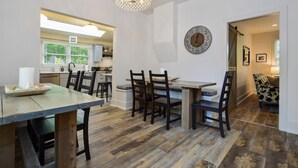 Un comedor con una mesa y sillas de madera, un candelabro y un reloj de pared.