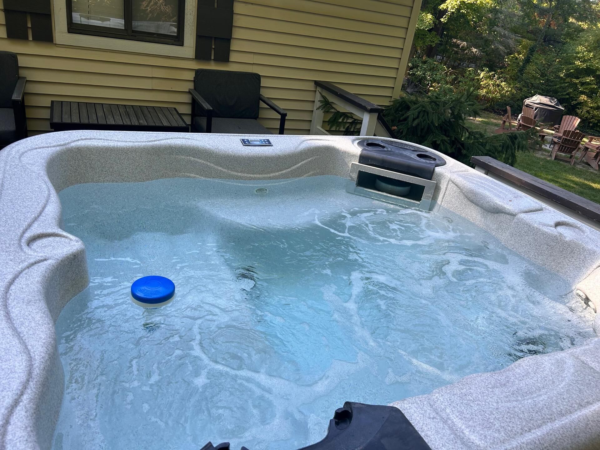 A hot tub with a blue lid, a control panel, and a window.
