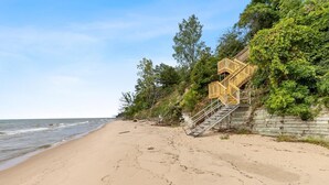 A beach with wooden stairs leading up to a building, surrounded by greenery.