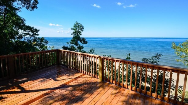 A wooden deck with a railing overlooking a beach and ocean.