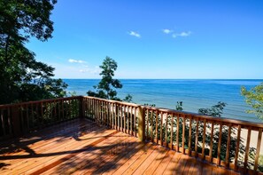 Une terrasse en bois avec une rambarde donnant sur une plage et l’océan.