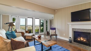 Una sala de estar con chimenea, televisor y vistas a través de puertas correderas grandes.