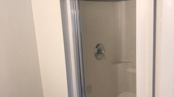 A glass-enclosed shower with a black tiled top, a chrome handle, and a visible drain.