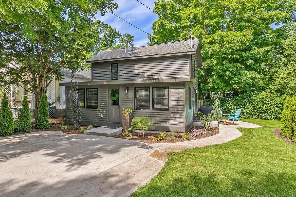 A two-story house with a front porch, a small garden, and a driveway.