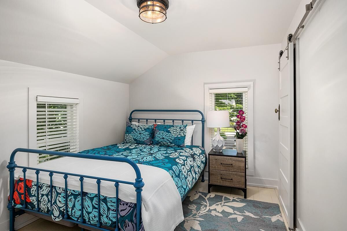 A bedroom with a bed, bedside table, lamp, and window.