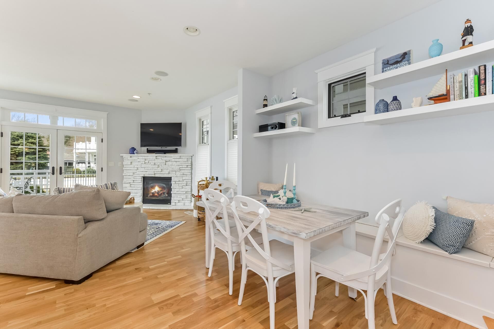 A modern living room with a fireplace, white furniture, and a bookshelf with decorative items.