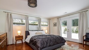 Une chambre à coucher avec un grand lit, deux tables de chevet avec des lampes, une commode en bois et un tapis coloré.