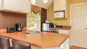 Una cocina con una isla grande, electrodomésticos de acero inoxidable, un microondas y lámparas colgantes.