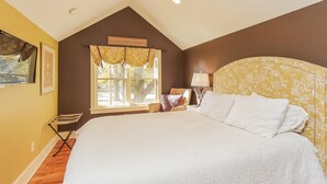 Un dormitorio con una cama grande, una ventana con cortinas, una lámpara y una silla.