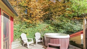 Un jacuzzi con dos sillas Adirondack y una terraza de madera.