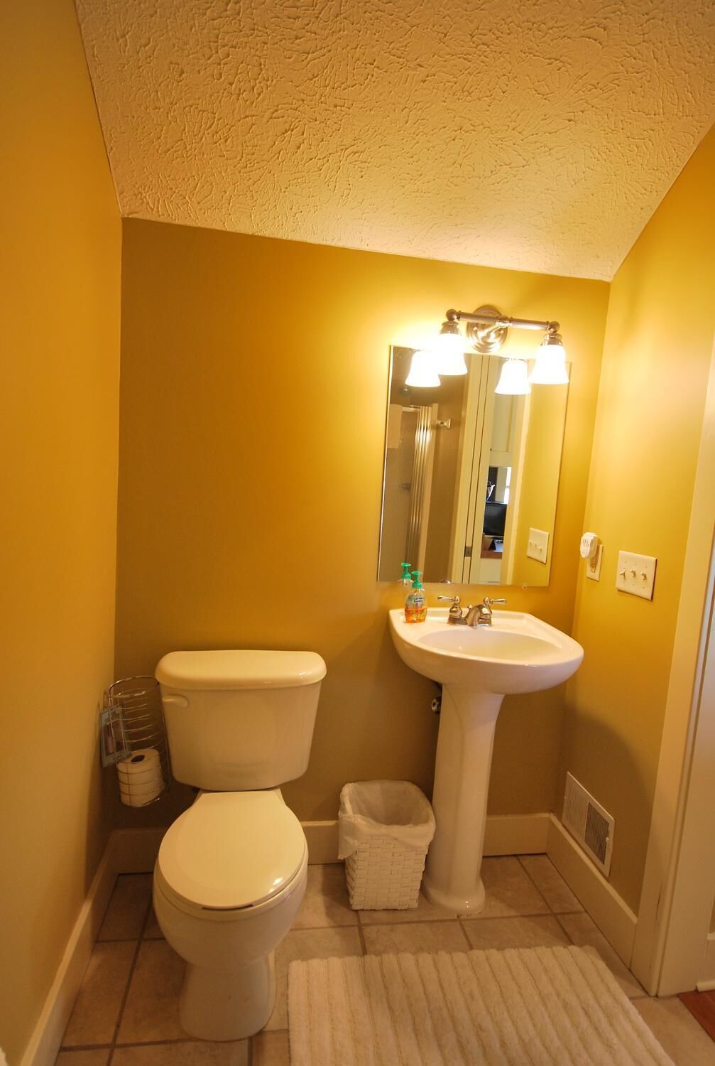 A small bathroom with a toilet, sink, and mirror.
