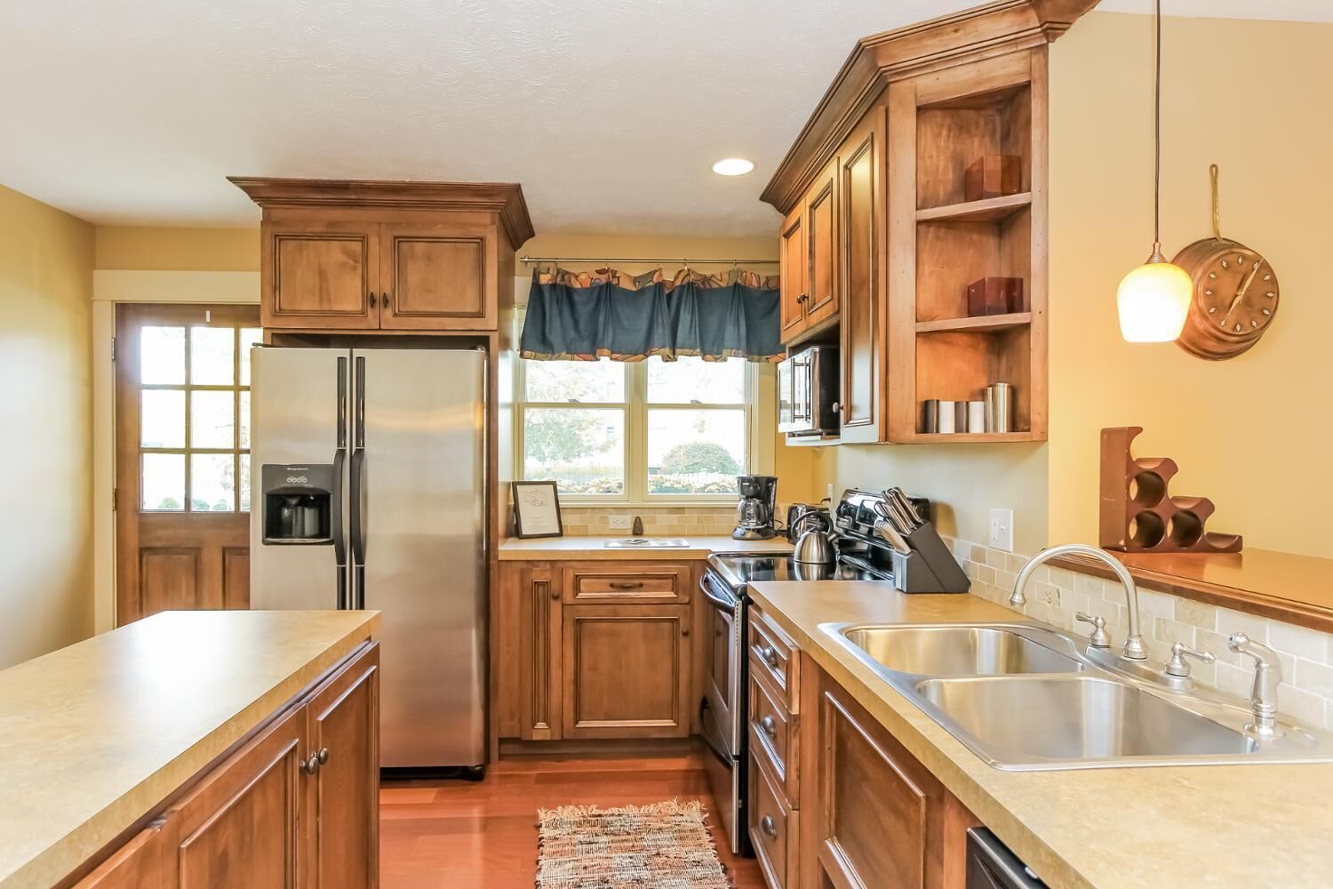 A kitchen with wooden cabinets, a stainless steel refrigerator, a sink, and a coffee maker.