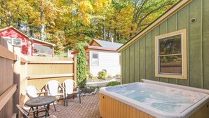 En trädgård med en bubbelpool, ett trädäck och ett litet förråd.