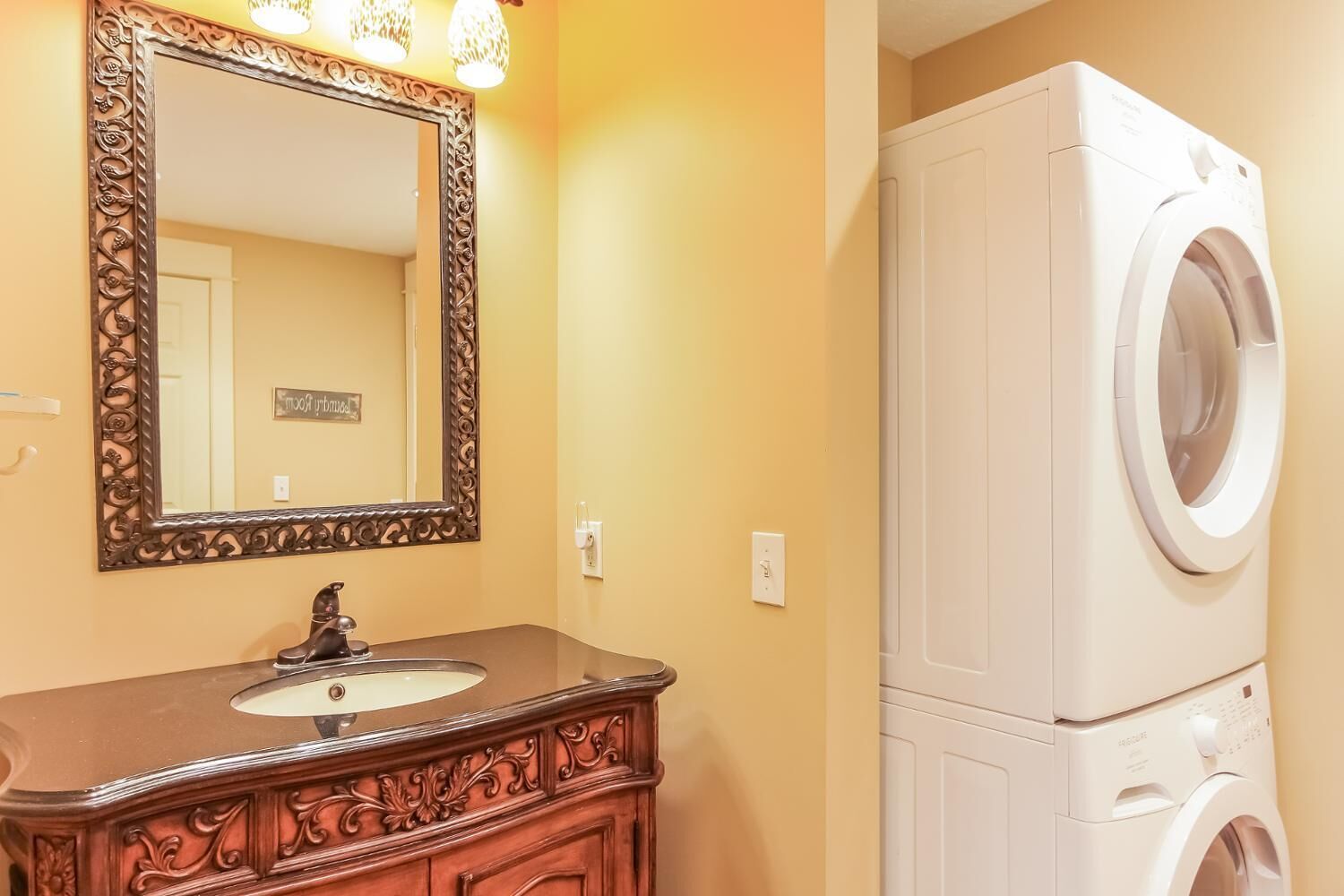 A bathroom with a wooden vanity, a large mirror, and a front-loading washing machine.