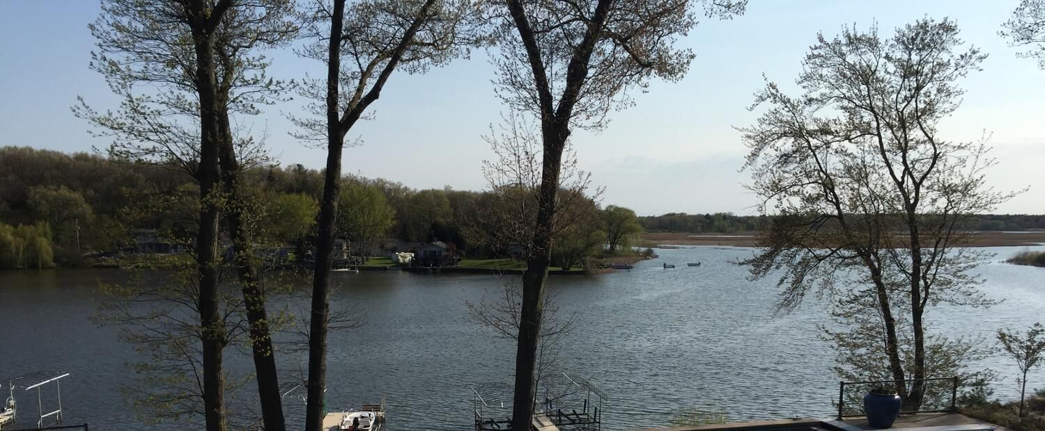 Une vue sur le lac, avec des arbres, un quai et des bateaux.