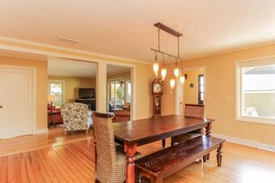 A dining room with a wooden table and chairs, a chandelier, and a clock on the wall.