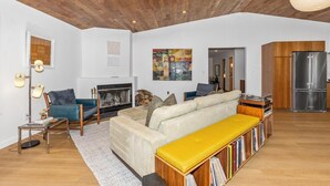 A spacious living room with a sofa, a coffee table, a fireplace, and a bookshelf. - How you Dune (Saugatuck)