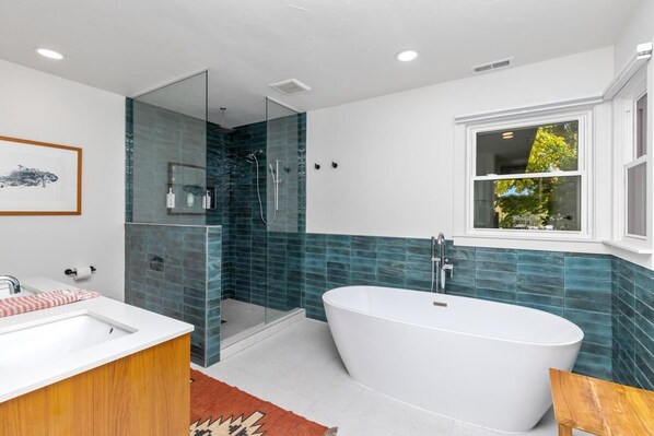 Une salle de bain moderne avec une baignoire sur pieds, une douche à parois de verre et une grande fenêtre.