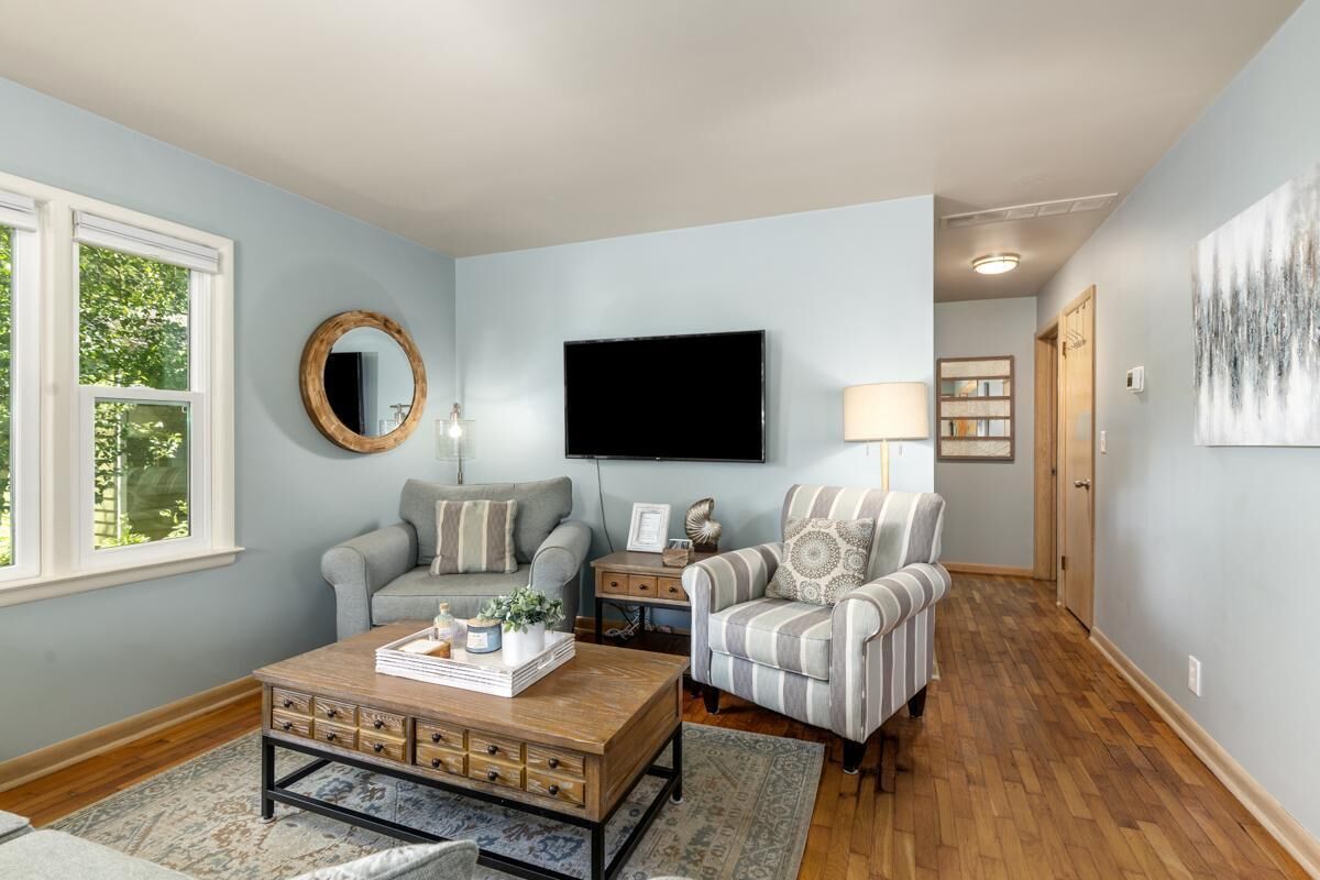 Una sala de estar con sofá, sillón, mesa de centro y televisor.