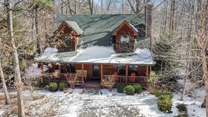 A cabin with a porch, two attached sheds, and a chimney.