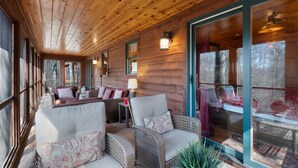 Een gezellig cabin interieur met houten wanden, een overdekte veranda en een zithoek met comfortabele fauteuils en een tafel.