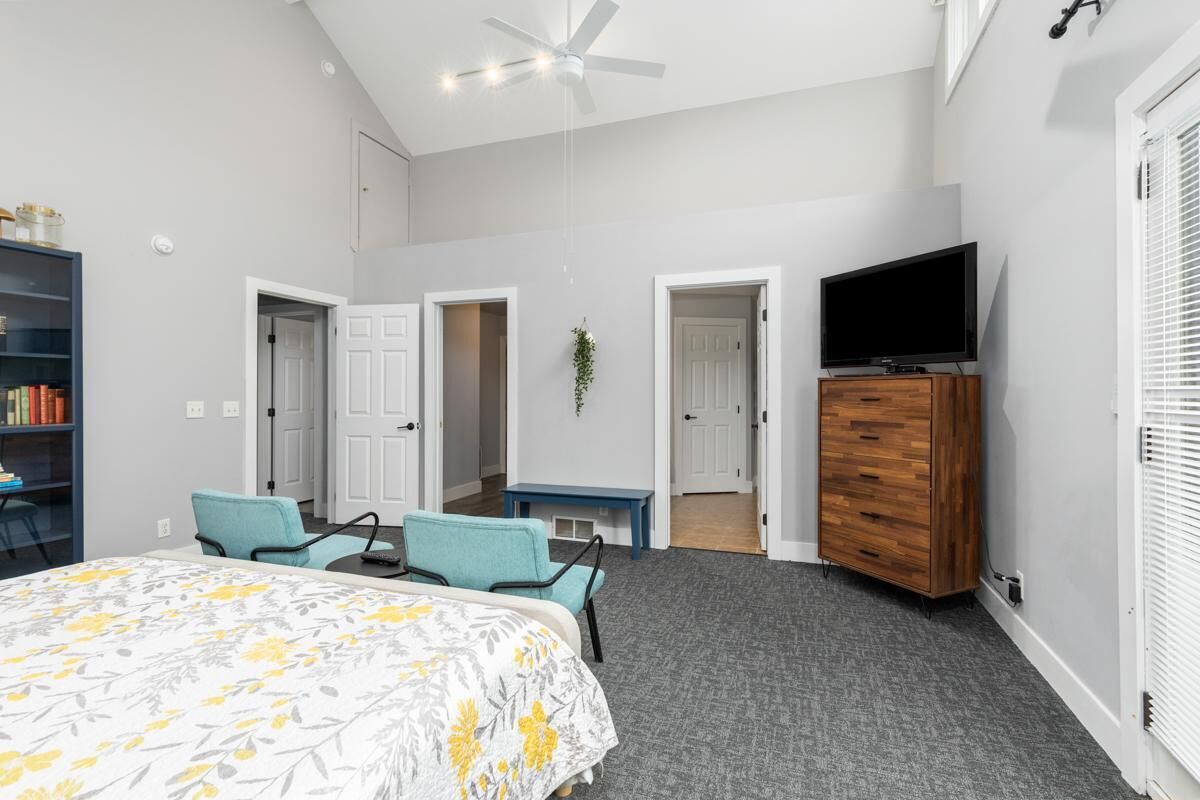 A modern bedroom with a bed, a desk, a TV, and a wardrobe.