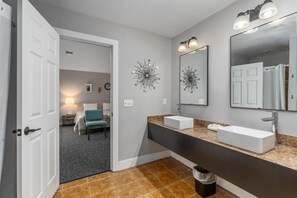A modern bathroom with a large mirror, two sinks, and decorative wall art.